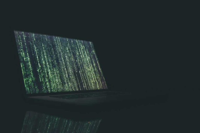 Code running down a laptop screen in a dark room